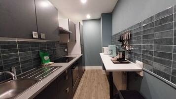 A modern kitchen with dark cabinets, a white countertop, and a tiled backsplash.