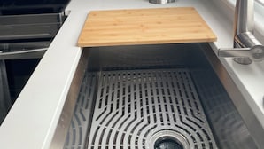 Una cocina con un lavamanos de acero inoxidable, encimera de madera y una ventana con persianas.