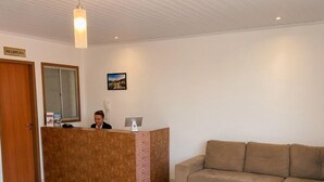 Una zona de recepción con un mostrador, un sofá y suelo de baldosas.