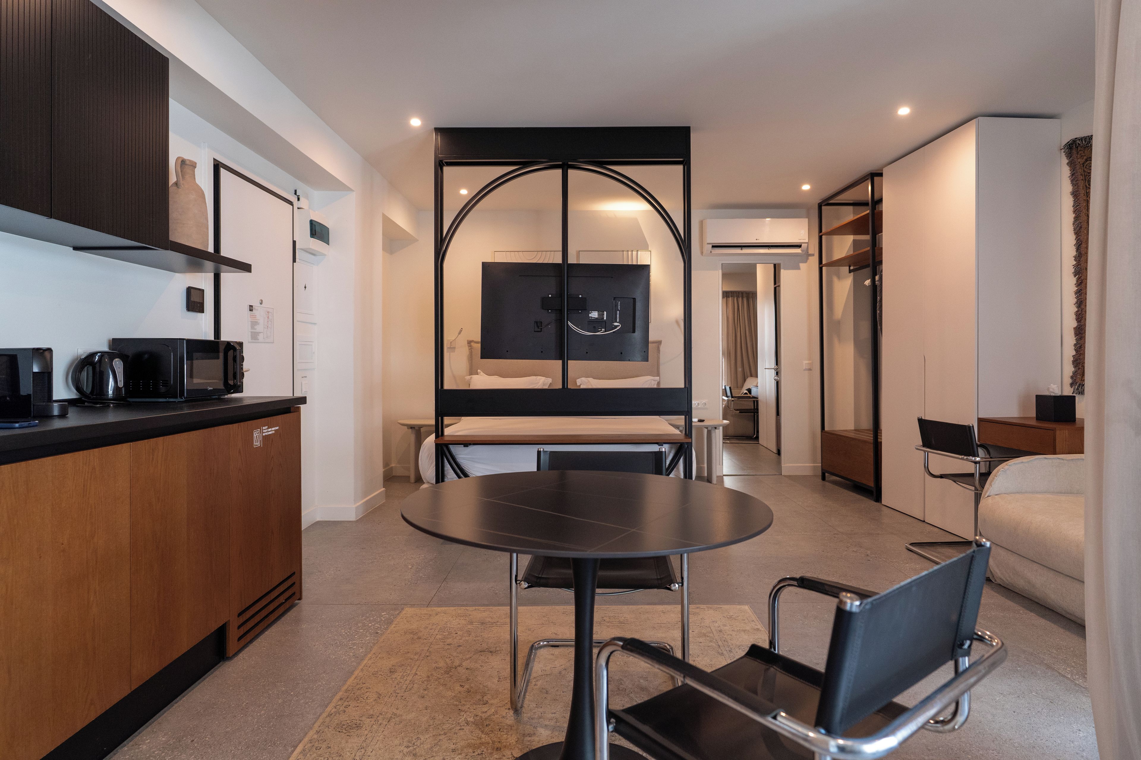 A modern hotel room with a kitchenette, a dining area, and a separate sleeping area.