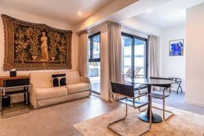 A modern living room with a sofa, a coffee table, and a dining area with chairs. - Fos (Athens)