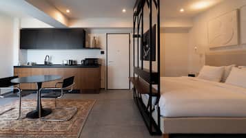 Une chambre d’hôtel moderne équipée d’un lit, d’un bureau, d’une kitchenette et d’une salle de bain.