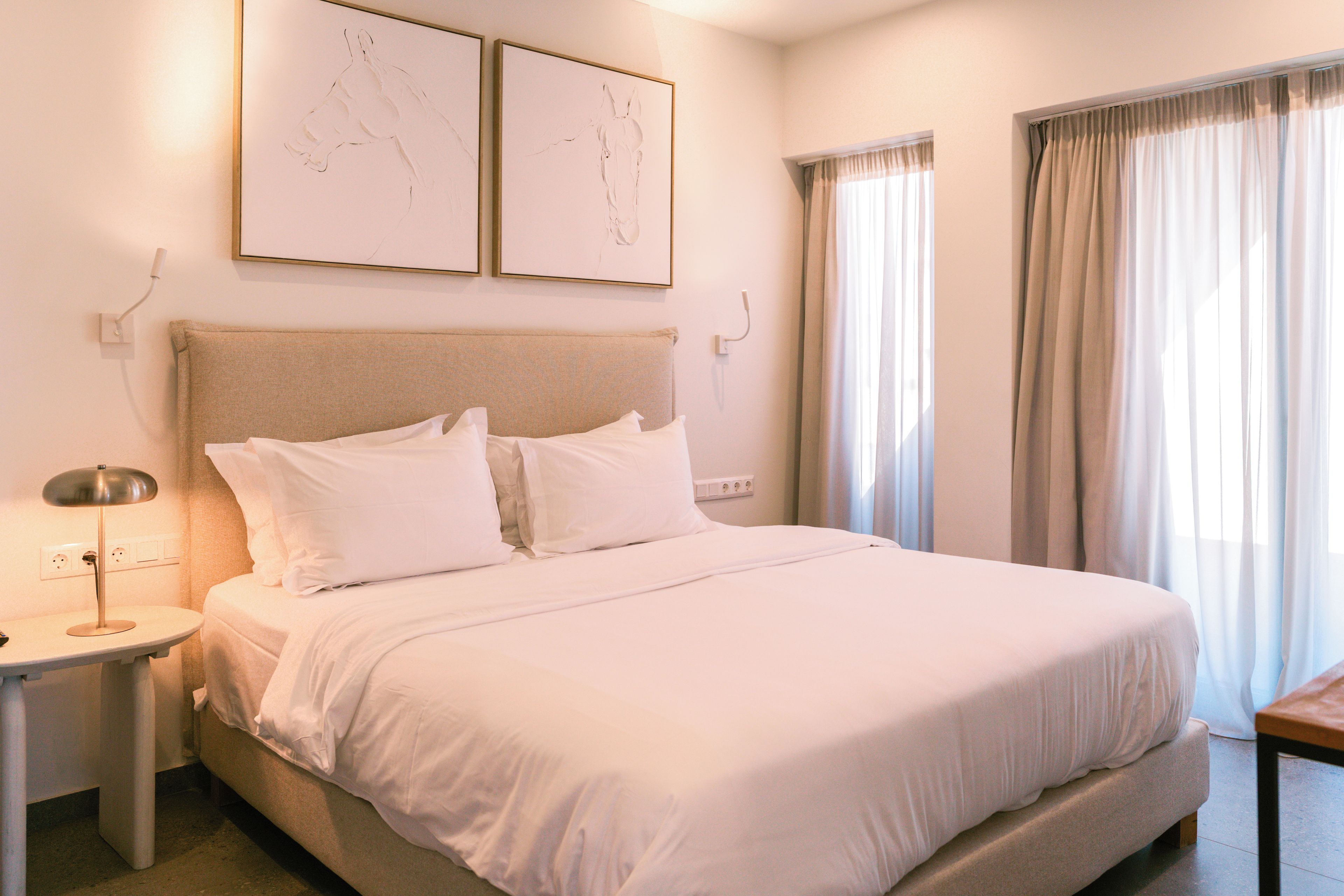 A neatly made bed with white linens in a hotel room.