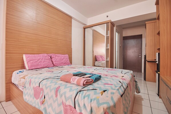 A bedroom with a bed, wooden wardrobe, and a mirror. - Room Rendi @ Gunung Putri Square by Zuzu (Gunung Putri)