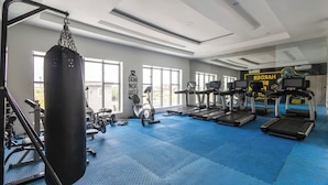 Une salle de sport équipée de matériel d’exercice, dotée de grandes fenêtres et affichant un message motivant.