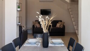 Un comedor moderno con una mesa rectangular, seis sillas y un florero con plantas secas.