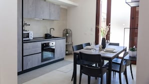 Una cocina moderna con electrodomésticos integrados, un comedor con mesa y sillas, y vistas al exterior a través de un ventanal.