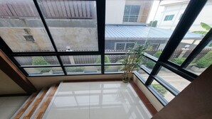 Quarto com grandes janelas, piso ladrilhado e planta em vaso.