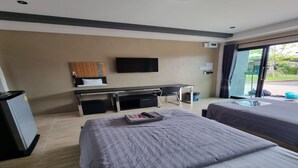Quarto de hotel com duas camas, uma escrivaninha, televisão e porta de correr para o exterior.