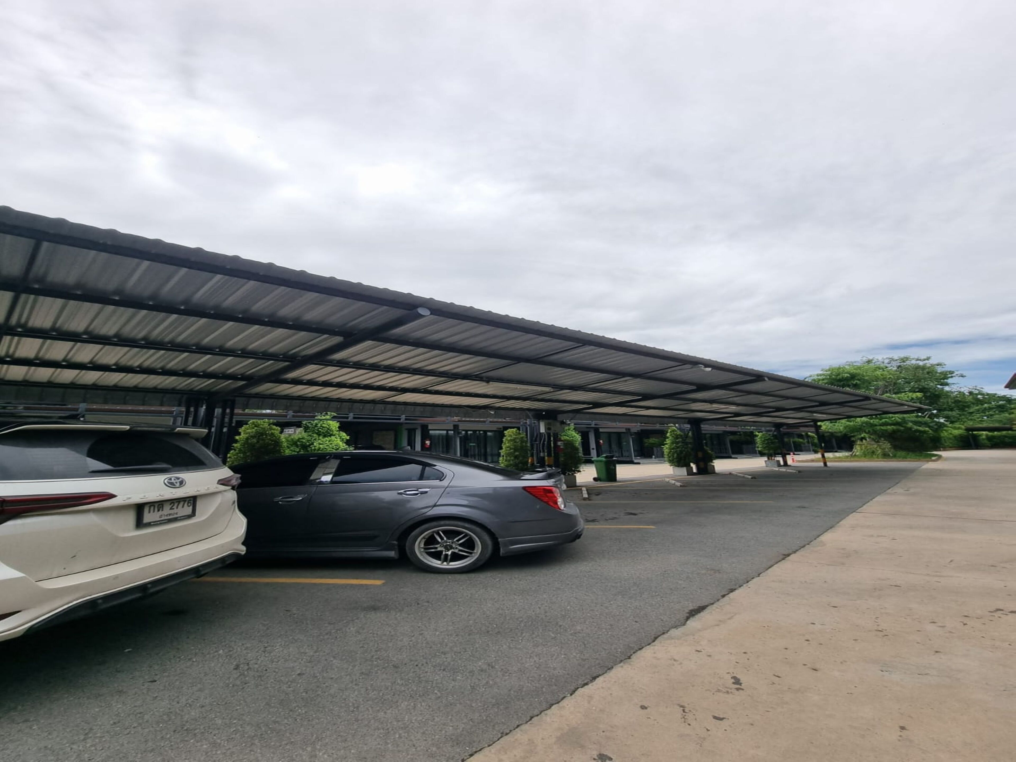 A covered parking area with two cars parked under a metal roof.