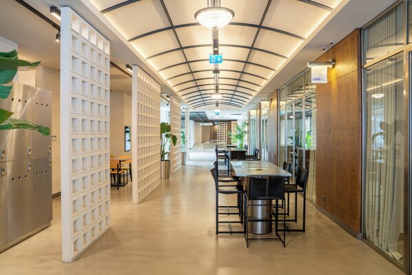A modern interior with a long corridor, a central table with chairs, and a ceiling with a grid pattern.
