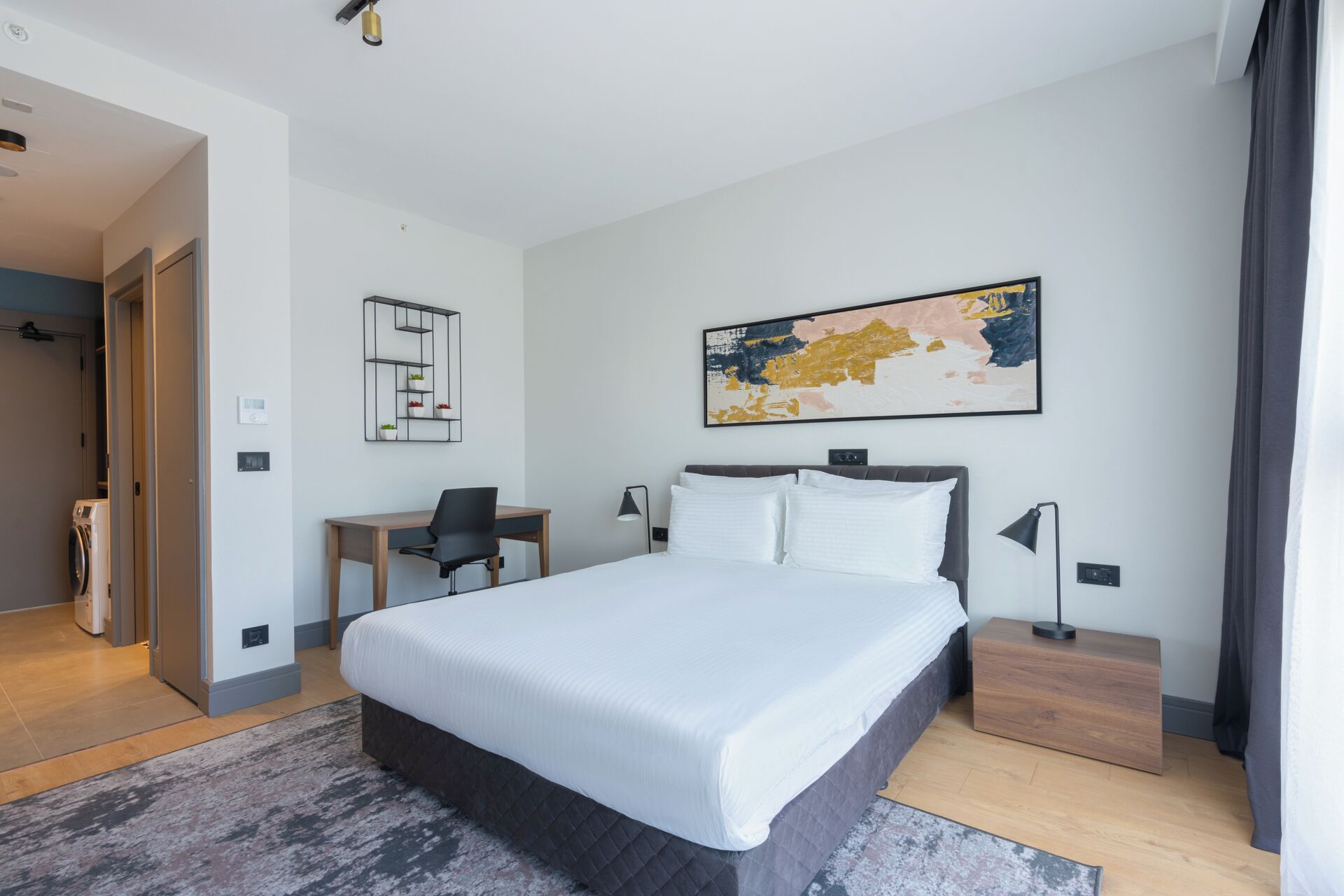 Quarto de hotel moderno com uma cama grande, uma escrivaninha e uma cadeira.