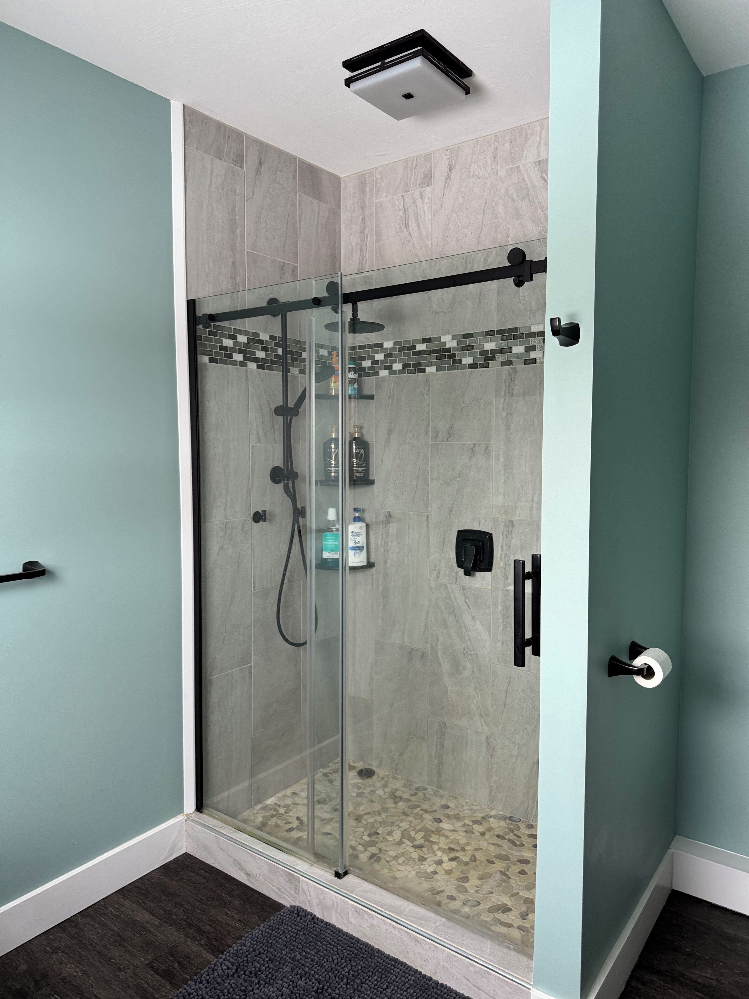 A modern bathroom with a glass-enclosed shower, a toilet, and a sink.