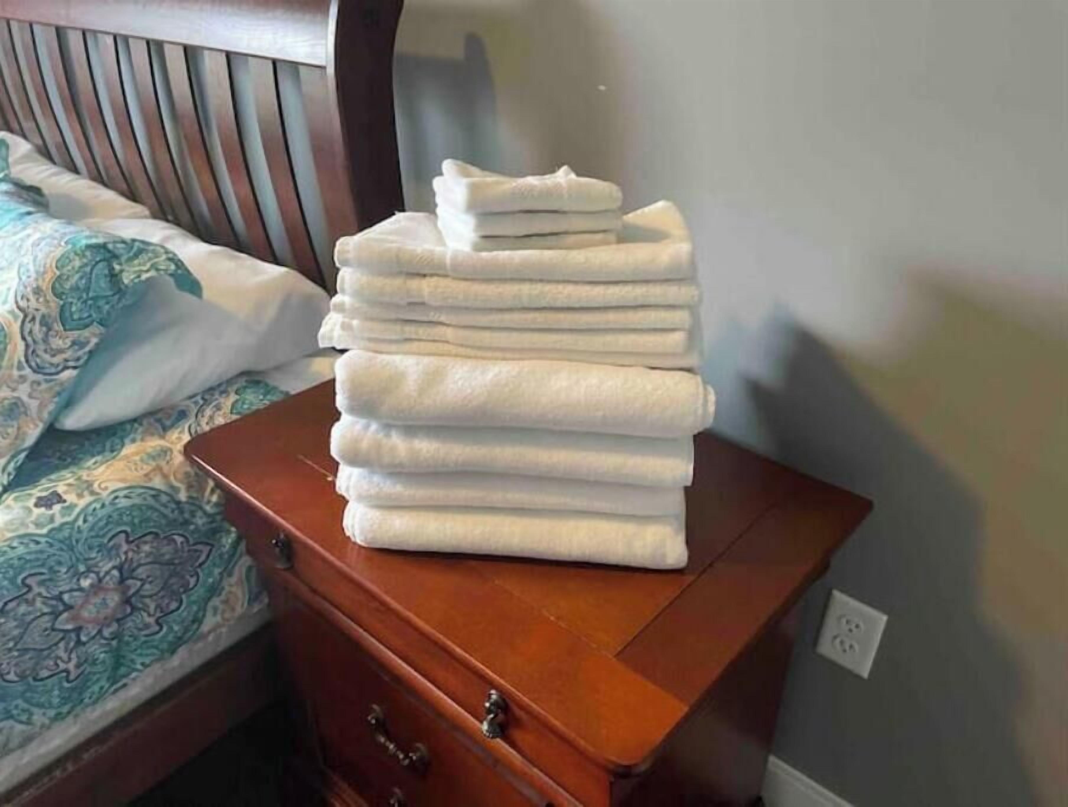 Una pila de toallas blancas sobre un aparador de madera en una habitación de hotel.