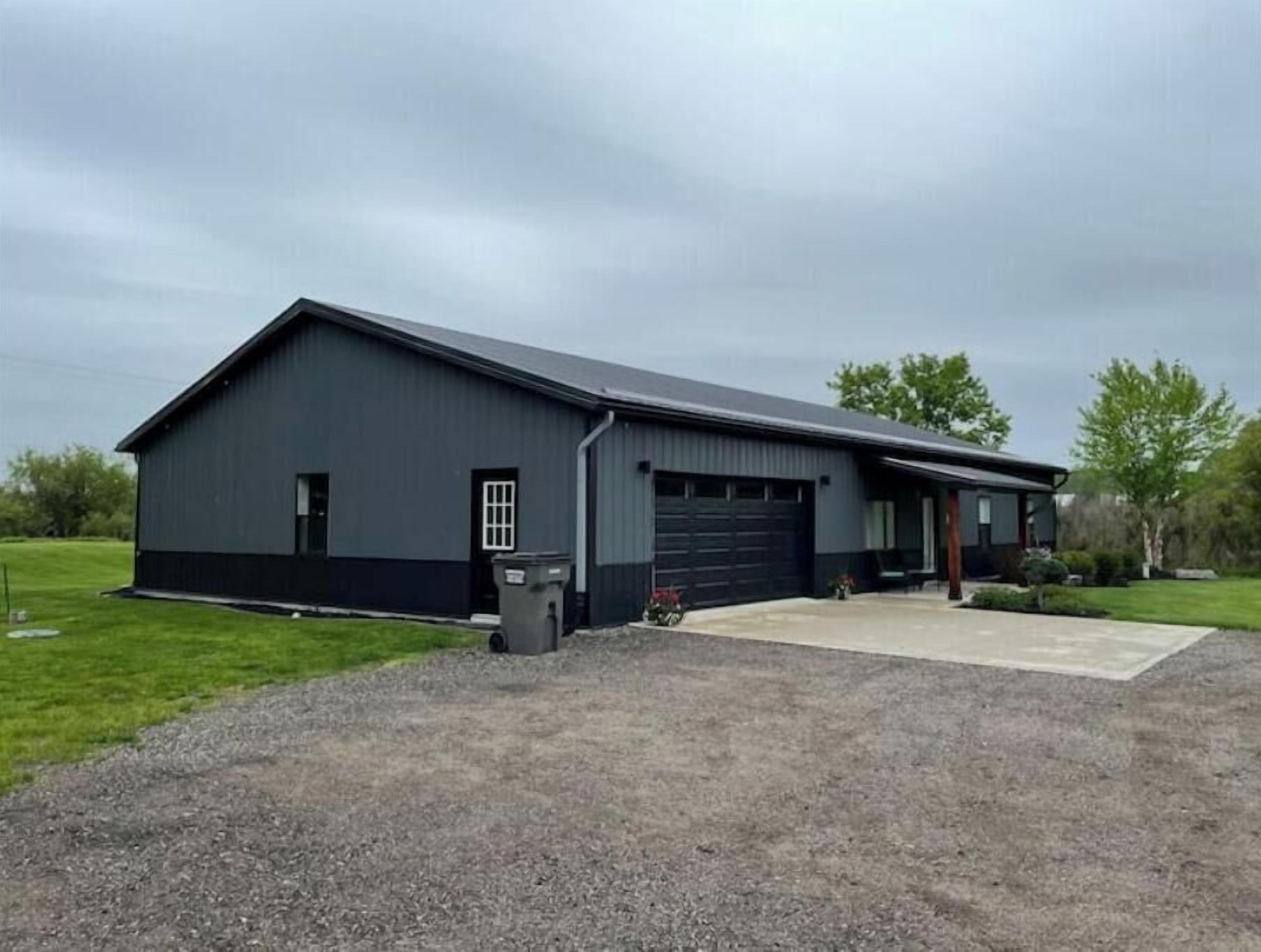 A single-story building with a dark exterior, a garage door, and a small porch area.
