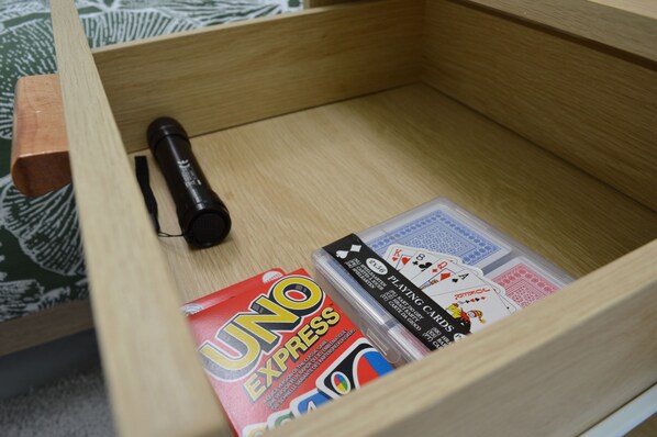 A wooden drawer with a flashlight, a UNO Express game, and a deck of playing cards.