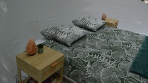 A tented room with a bed, two pillows, a small table with a salt lamp, and a potted plant. - Bubble Tent Loiret: nature and comfort, close to the Loire castles (Chuelles)