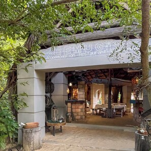 L'ingresso di un ristorante rustico, caratterizzato da un arco in pietra, travi in legno e una targa.