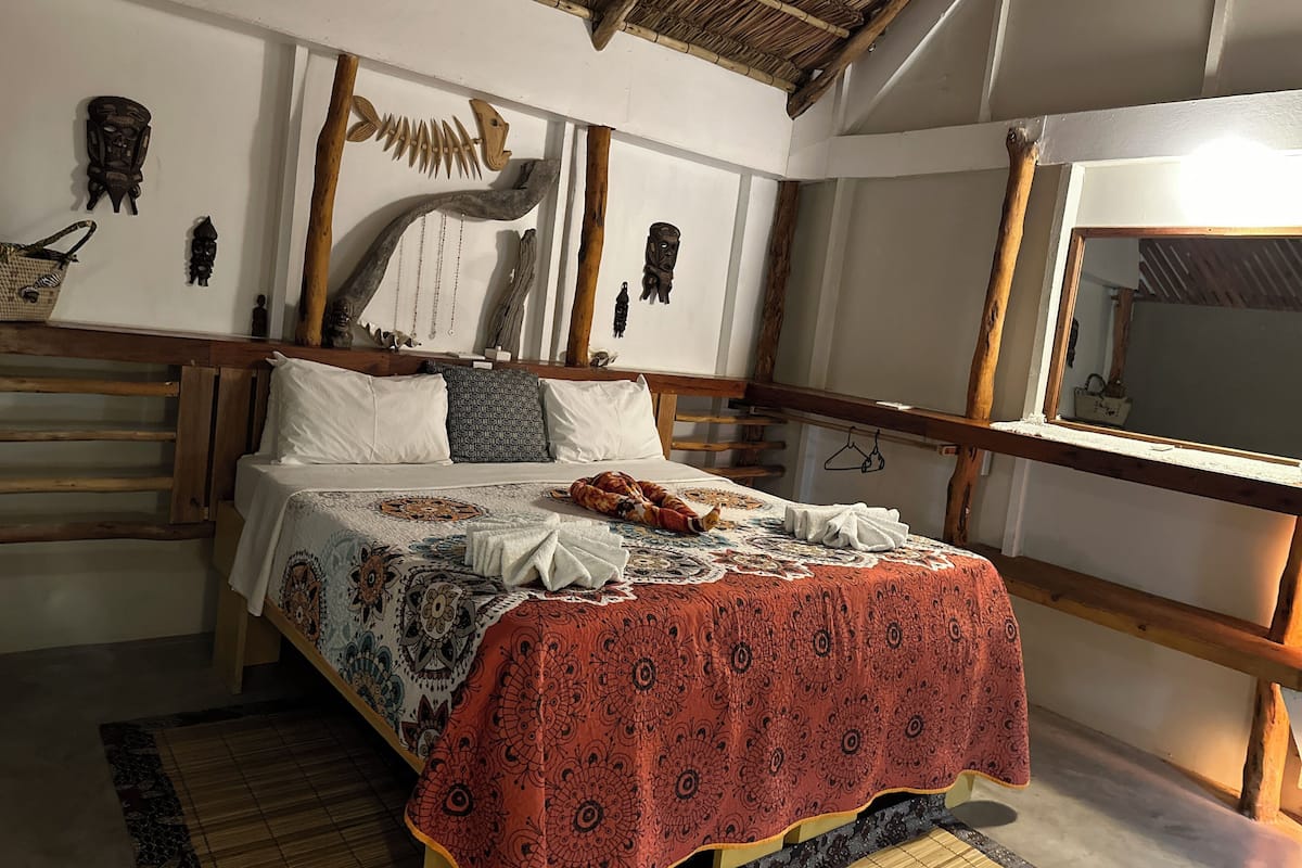 Ein Bett mit einem gemusterten Überwurf, einem Holzkopfteil und einer rustikalen Decke.