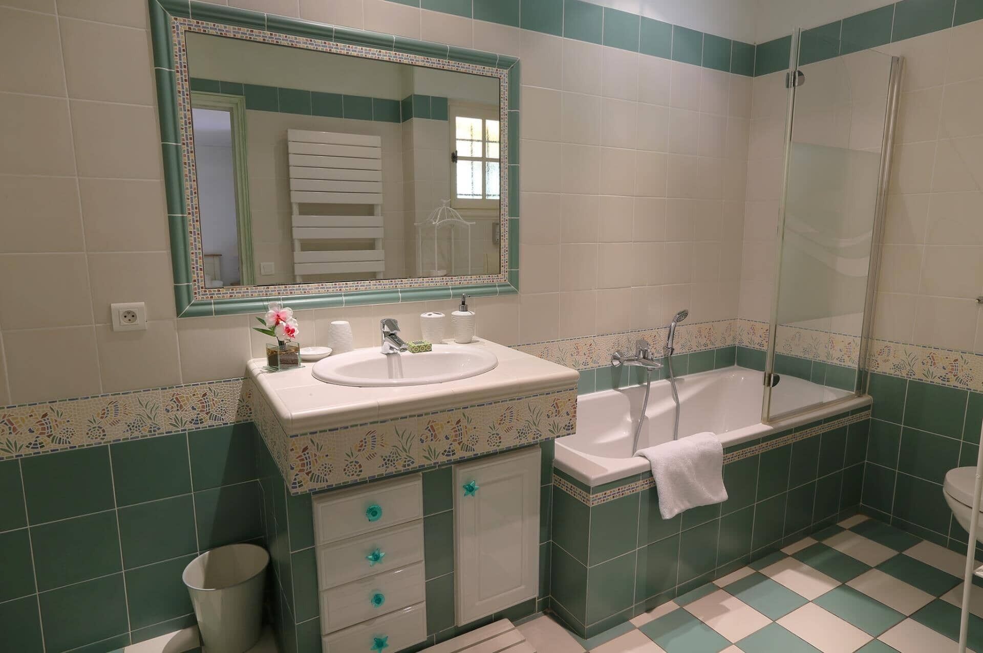 Een badkamer met een wastafel, spiegel, badkamermeubel, bad en toilet.