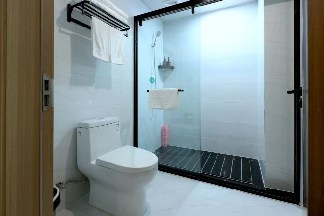 A modern bathroom with a toilet, a glass shower enclosure, and a towel rack.