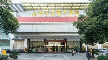 A hotel entrance with a large sign, a covered entrance, and a person standing near the entrance.