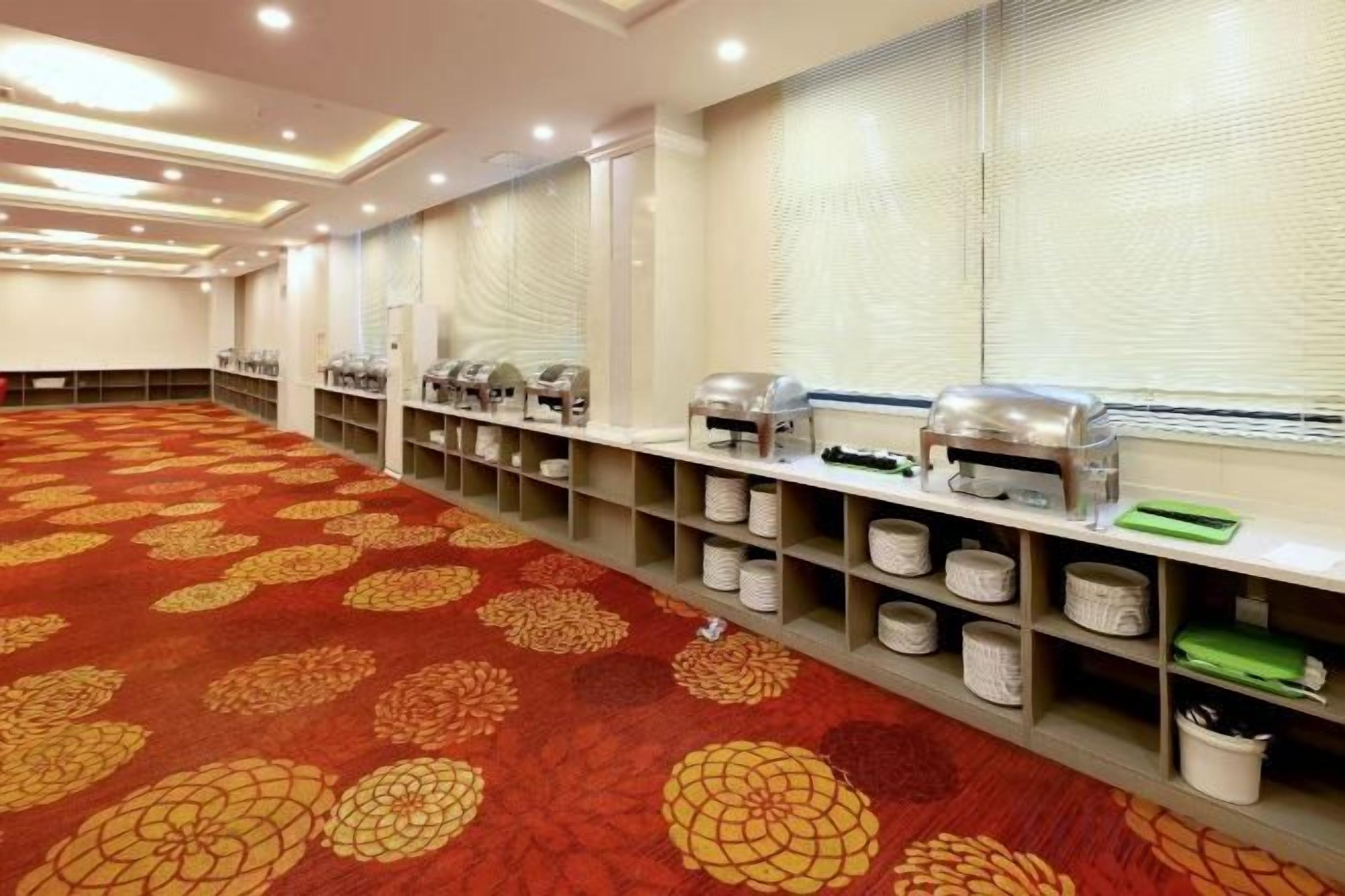 A conference room with a patterned carpet, buffet setup, and a long table.