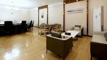Habitación de hotel con piso de madera, una mesa de comedor con sillas, un sofá y una mesita con una computadora portátil.