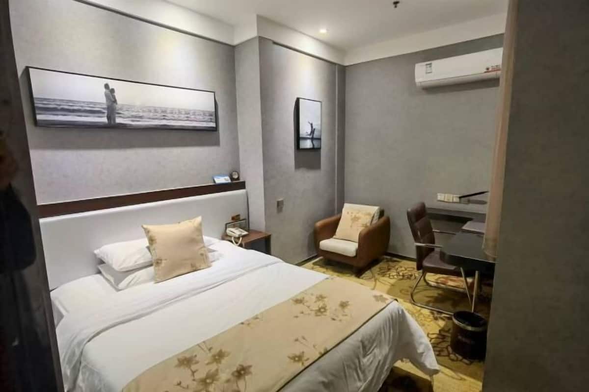 Une chambre d’hôtel équipée d’un lit, d’une chaise, d’un bureau et d’un climatiseur fixé au mur.