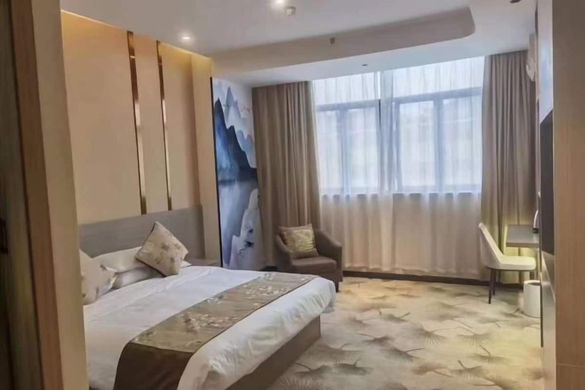 Une chambre d’hôtel avec un grand lit, une chaise, un bureau et un tableau au mur.