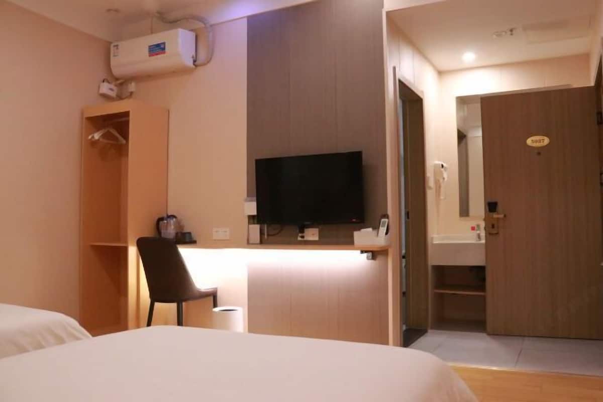 Une chambre d’hôtel comprenant un lit, un bureau avec une chaise, une télévision, une armoire et une porte de salle de bain.