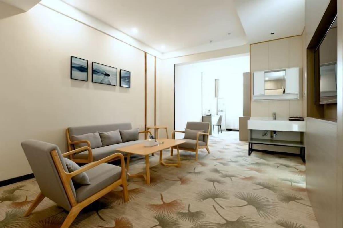 Un salón moderno con un sofá, sillones, una mesa de centro y obras de arte en la pared.