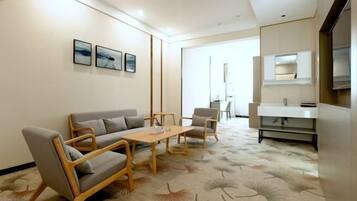 Un salón moderno con un sofá, sillones, una mesa de centro y obras de arte en la pared.