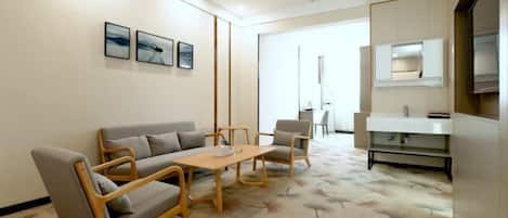 A modern living room with a sofa, chairs, a coffee table, and artwork on the wall.