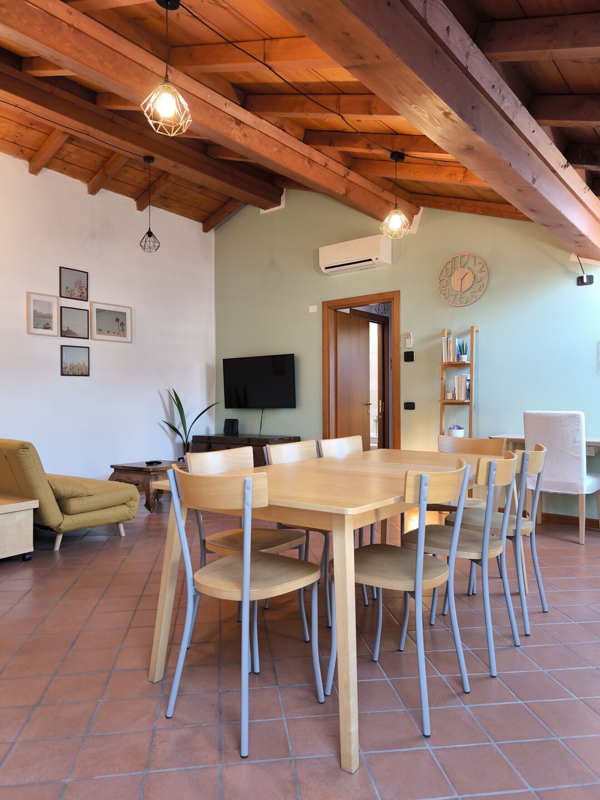 A dining area with a wooden table and chairs, a television, and a bookshelf.