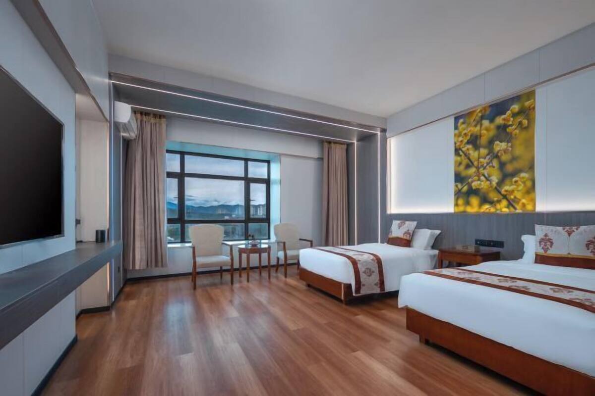 Una habitación de hotel con una cama grande, una cama más pequeña, un escritorio, una silla y un televisor.