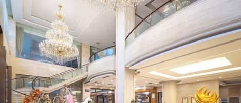 A spacious atrium with a grand chandelier, a central column, and a staircase.