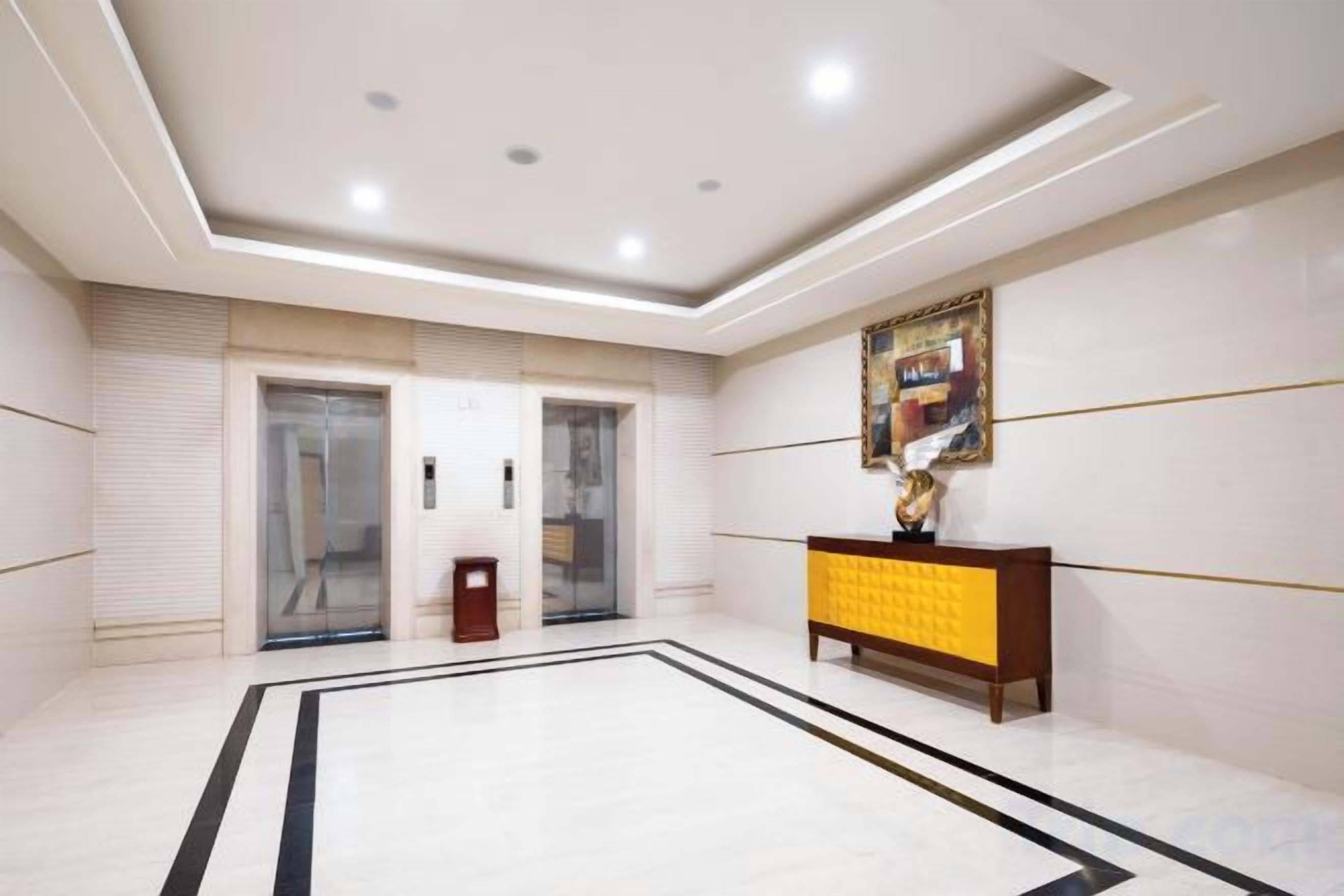 A hotel lobby with a marble floor, a reception desk, and a framed artwork on the wall.