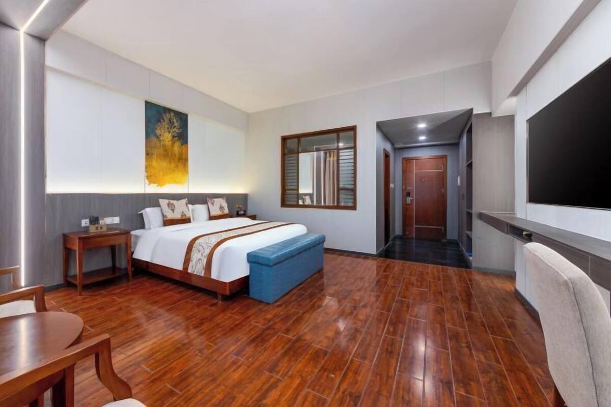 Una habitación de hotel con cama, mesita de noche, banco y televisión.