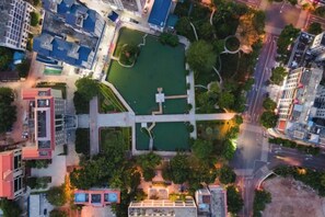 Vista aérea de un paisaje urbano con un parque verde central, edificios circundantes y una cuadrícula de calles.