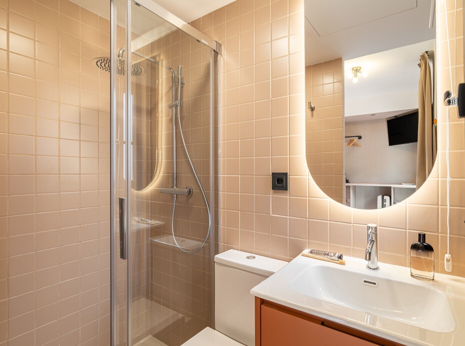 Een moderne badkamer met een douche met glazen wand, een wit wastafelmeubel en een grote spiegel.