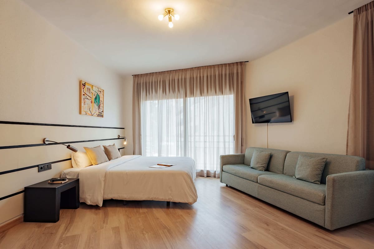 A modern bedroom with a bed, bedside table, and a sofa.