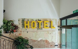 Hotel entrance features a vintage sign and lush greenery.