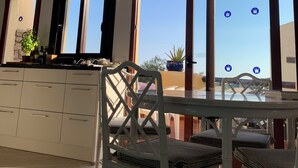 A modern kitchen with white cabinets, a dining table with chairs, and large windows offering a view of the outdoors. - Beautiful, comfortable home in the heart of the sought-after Manga Club (Cartagena)
