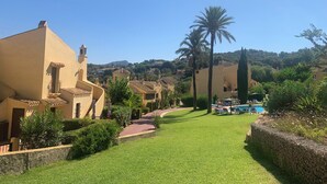 A residential area with Mediterranean-style buildings, a well-maintained lawn, and a swimming pool. - Beautiful, comfortable home in the heart of the sought-after Manga Club (Cartagena)