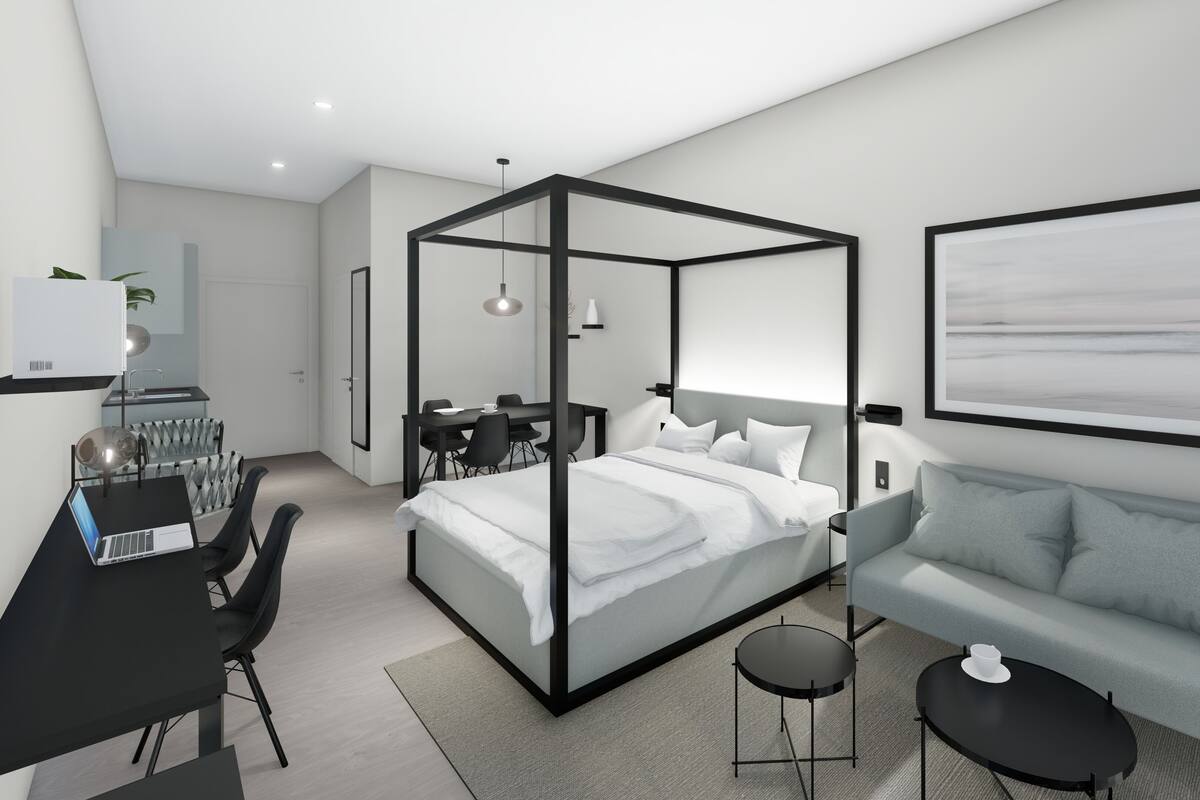 A modern hotel room with a four-poster bed, a desk with a laptop, a dining area, a sofa, and a large framed artwork on the wall.