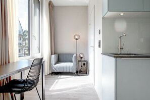 A modern kitchen with a built-in sink, a dining area with a chair, and a floor lamp. - VISIONAPARTMENTS St Gallen (St. Gallen)