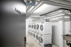 A laundry facility with multiple washing machines and a large industrial dryer. - VISIONAPARTMENTS St Gallen (St. Gallen)