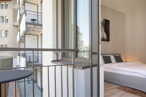 A modern bedroom with a bed, a window, and a balcony with a table. - VISIONAPARTMENTS St Gallen (St. Gallen)
