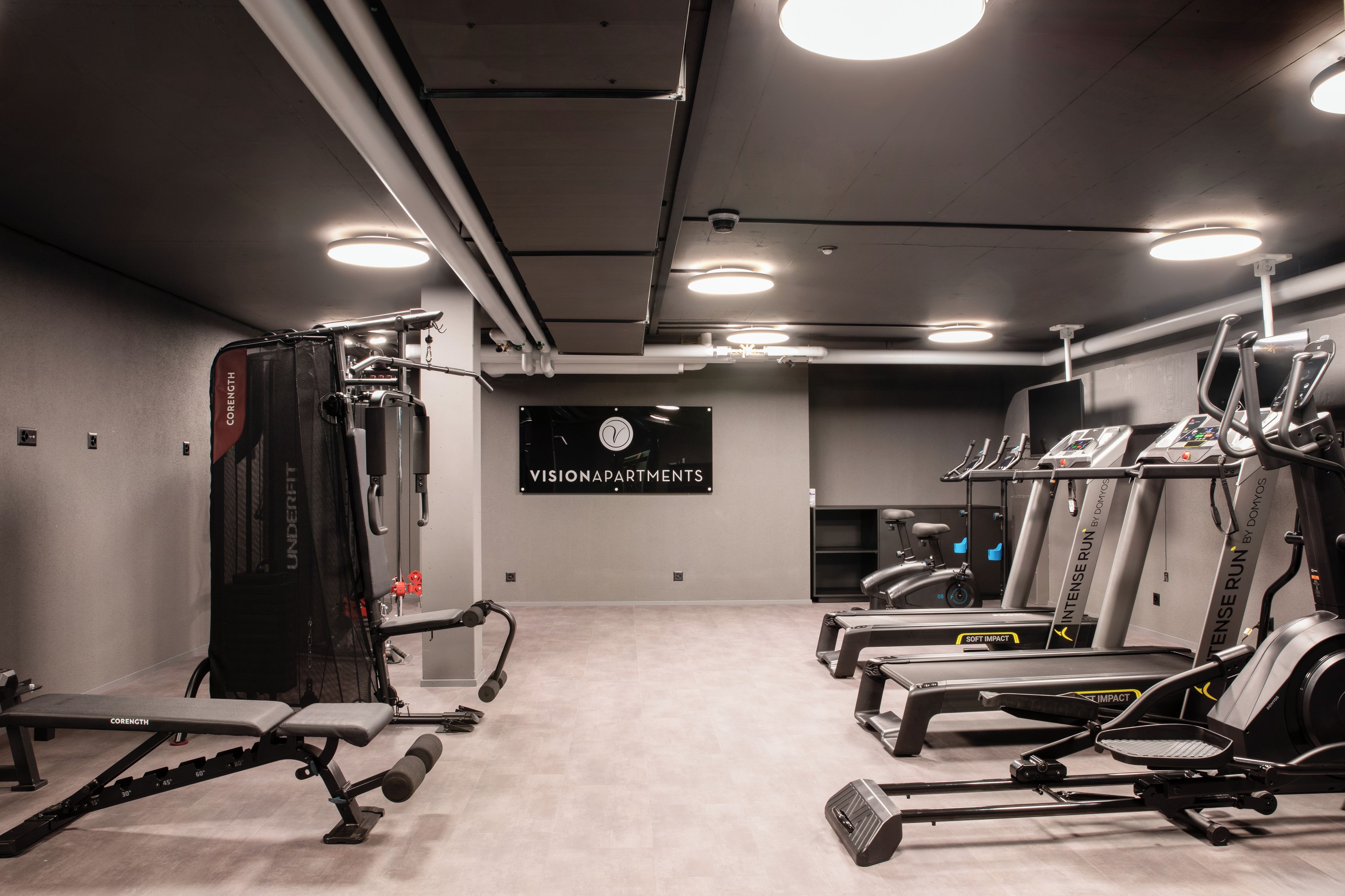 A gym with various exercise equipment including a squat rack, treadmills, and a bench press.